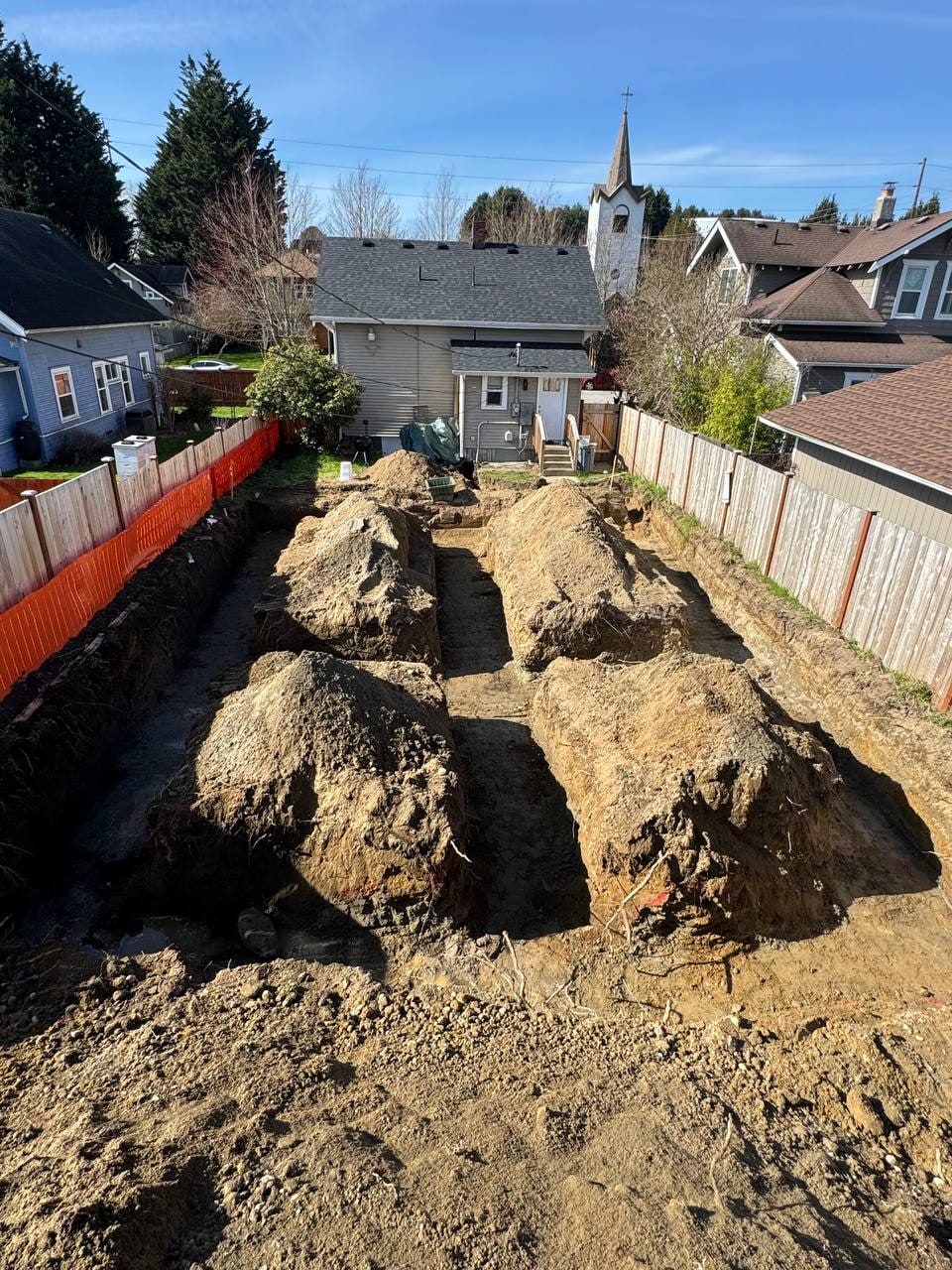 Backyard ADU excavation with soil piles by Artbrick in Snohomish County