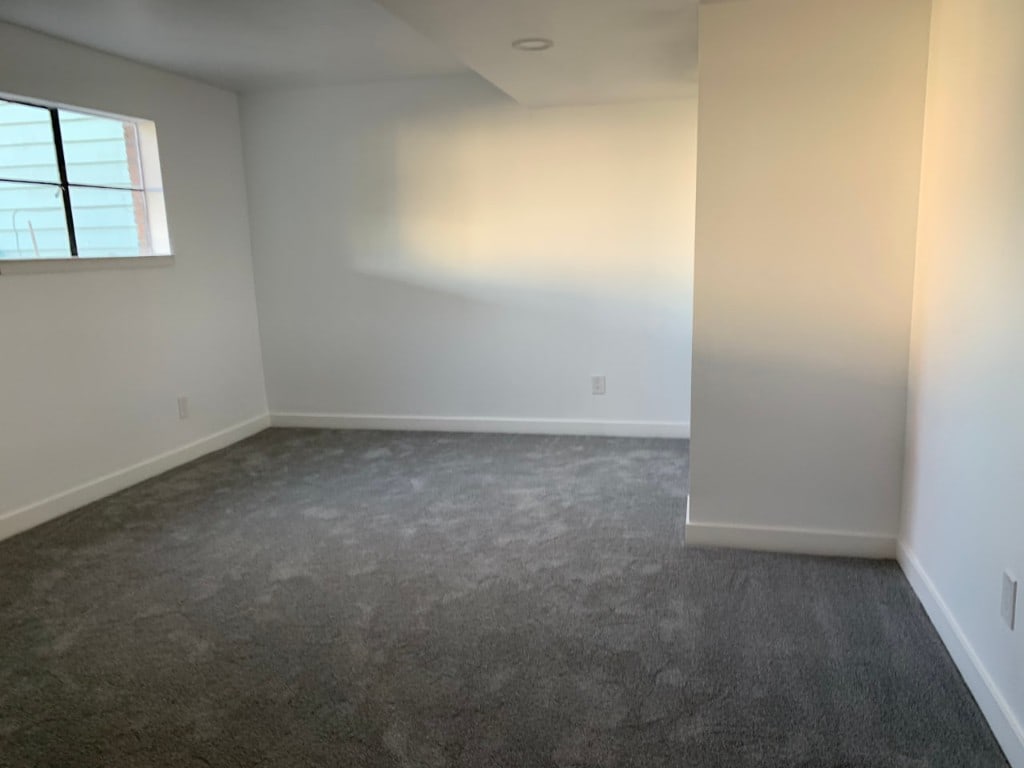 Finished basement bedroom with a window and gray carpet by Artbrick