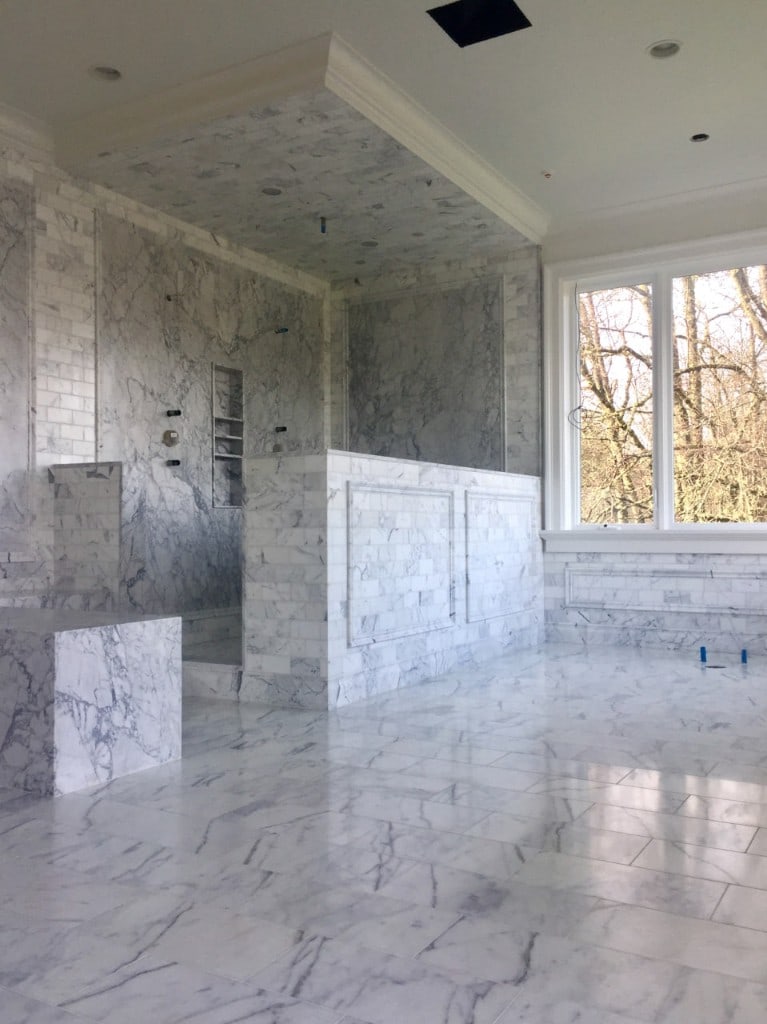 Primary bathroom with full Carrara marble walls, shower niche, and tile wainscoting by Artbrick