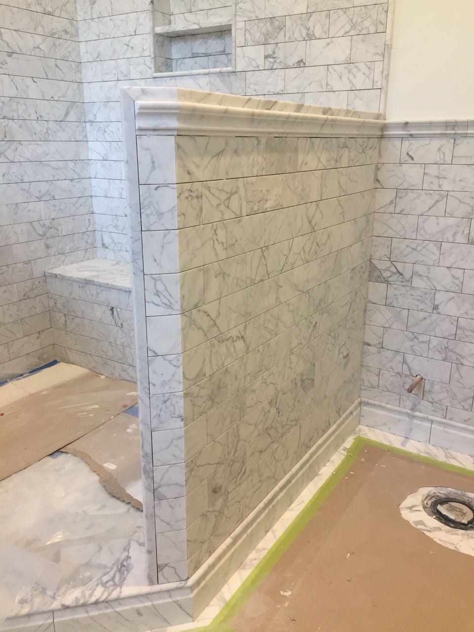 Marble subway tile shower with pony wall by Artbrick