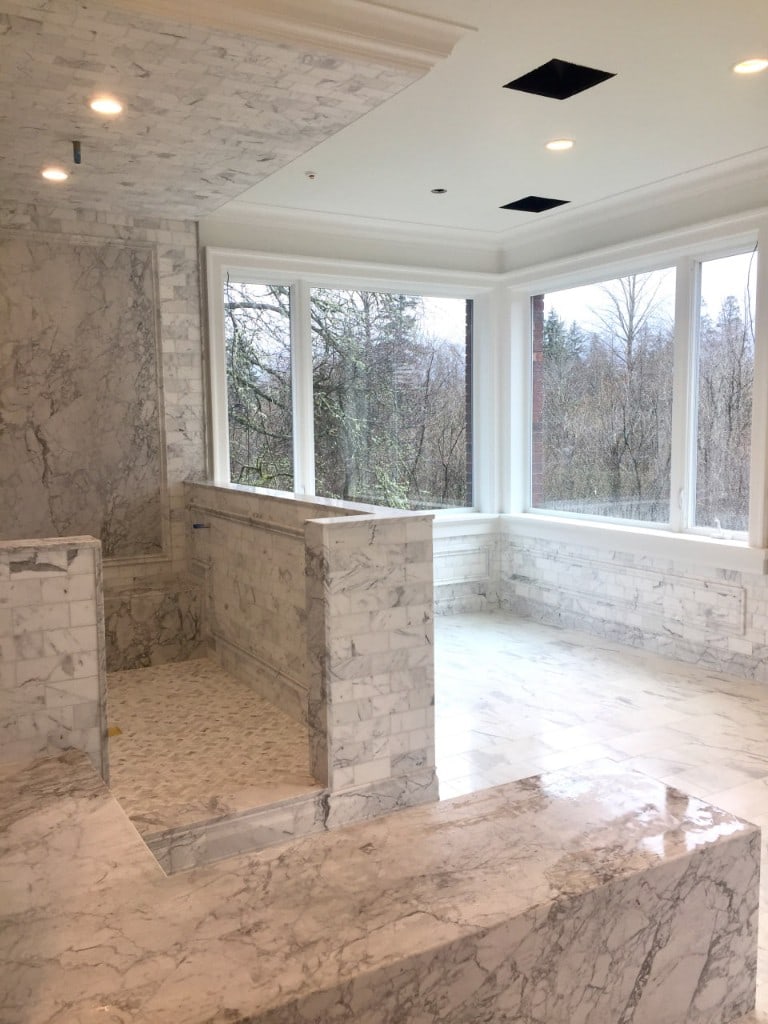 Marble wet room with a curbless shower and corner windows by Artbrick