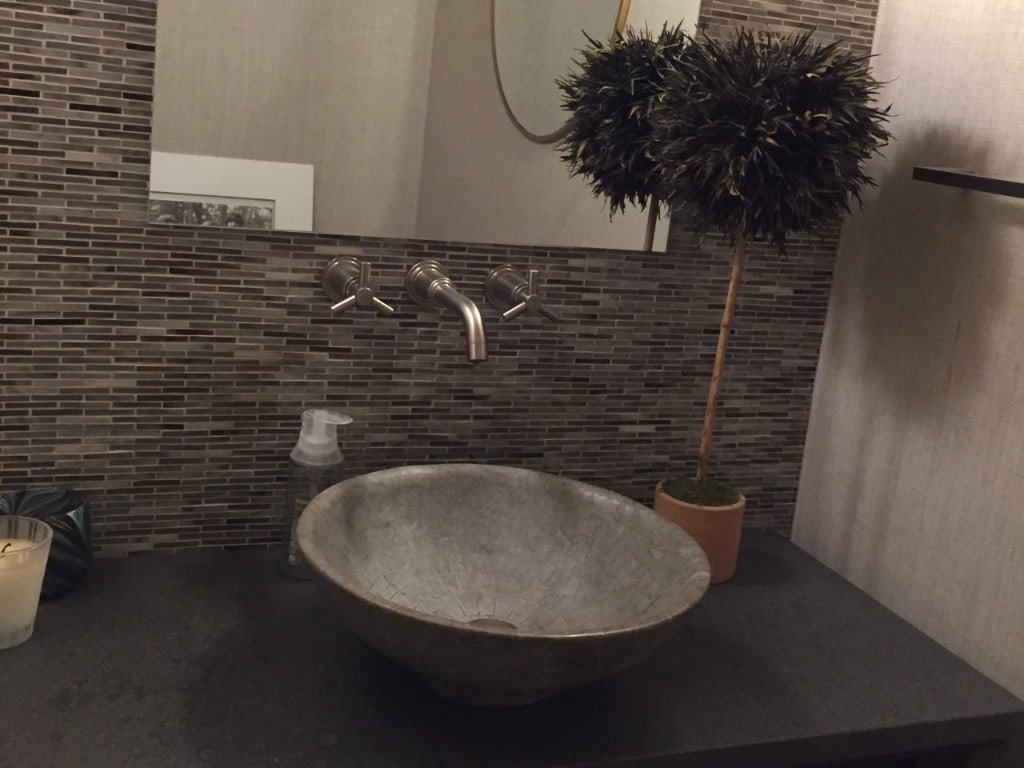 Powder bath with a stone vessel sink, wall-mounted faucet, and linear mosaic tile backsplash by Artbrick