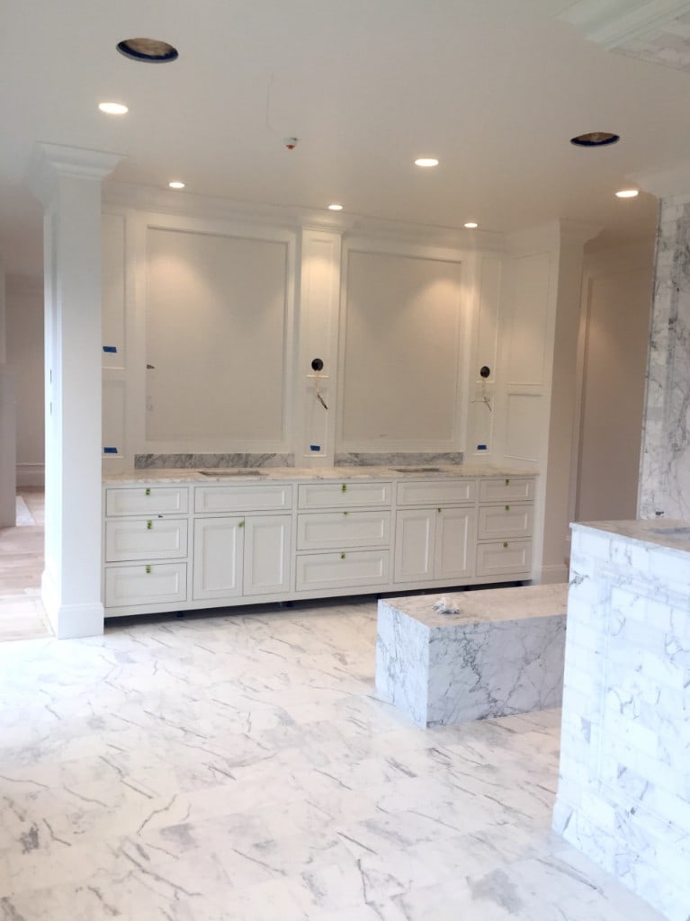 Primary bathroom with a white double vanity, marble countertop, and marble tile floor by Artbrick