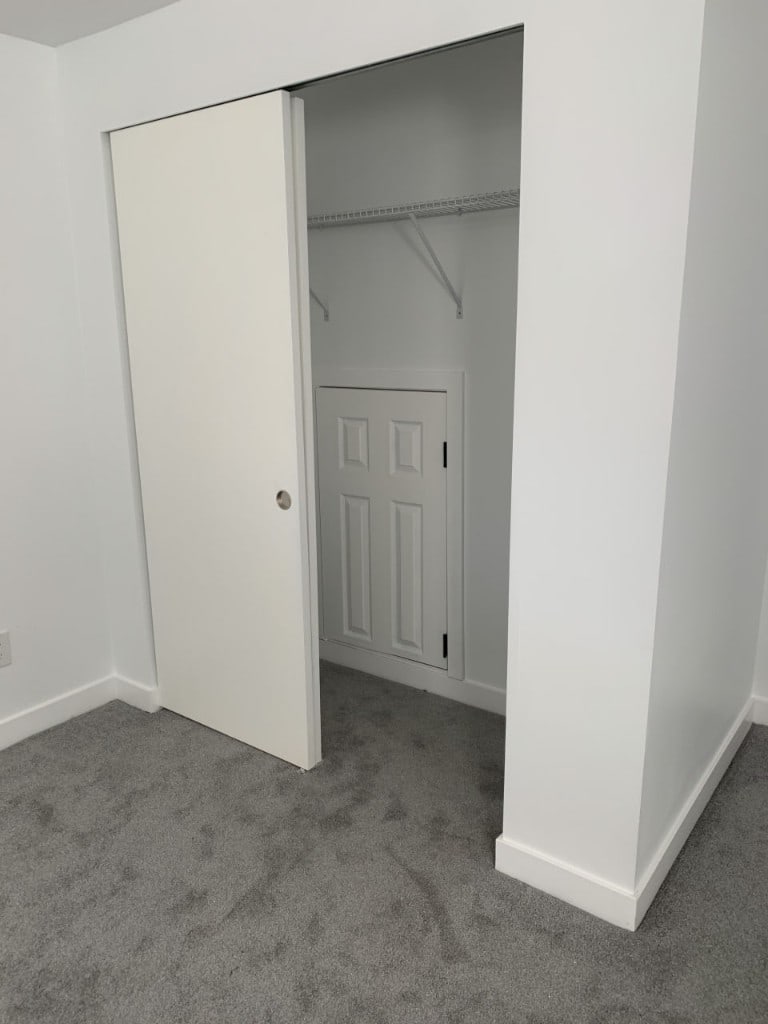 Bedroom closet with a sliding door, wire shelving, and access door by Artbrick