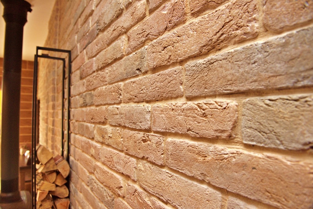 Decorative faux brick plaster feature wall beside a wood stove by Artbrick