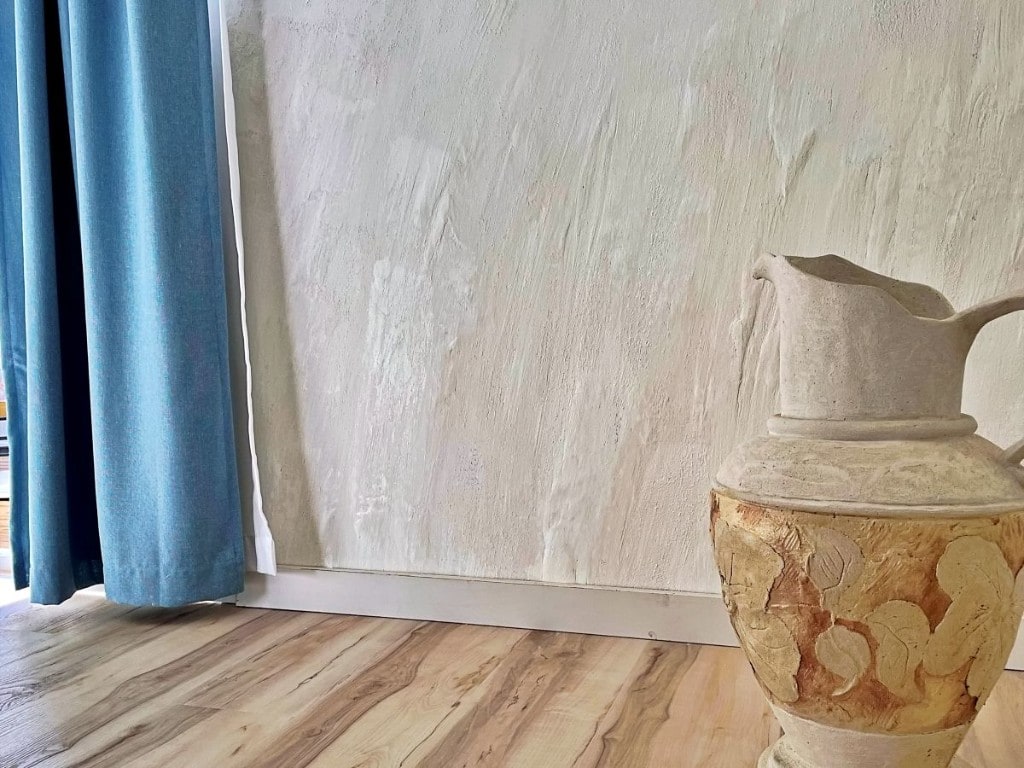 Decorative plaster amphora with leaf relief beside a plastered feature wall by Artbrick