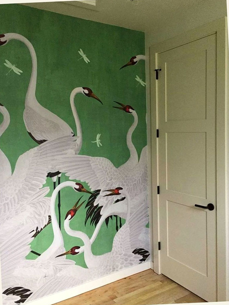 Hand-painted crane mural on green wall by Artbrick