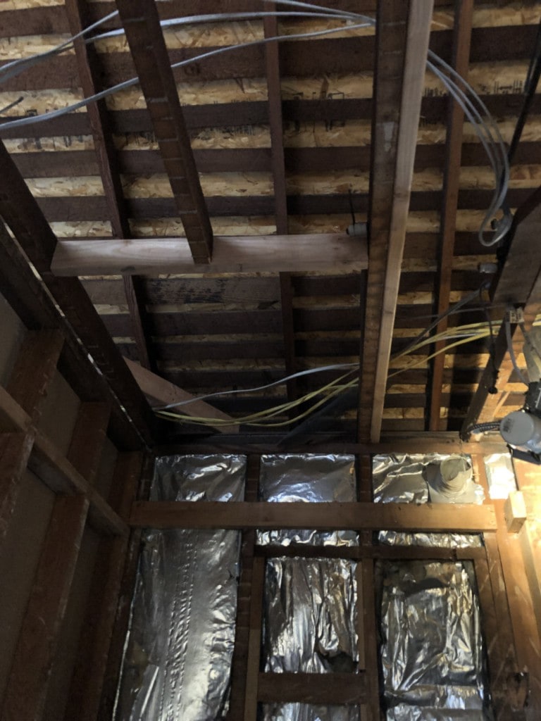 Roof rafters, insulation, and wiring exposed during interior demolition by Artbrick