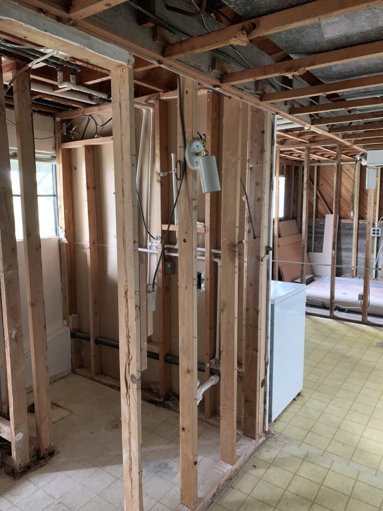 Interior demolition with stud walls and plumbing exposed during a gut remodel by Artbrick