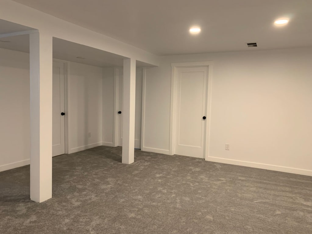 Repainted basement family room with columns, doors, and recessed lighting by Artbrick