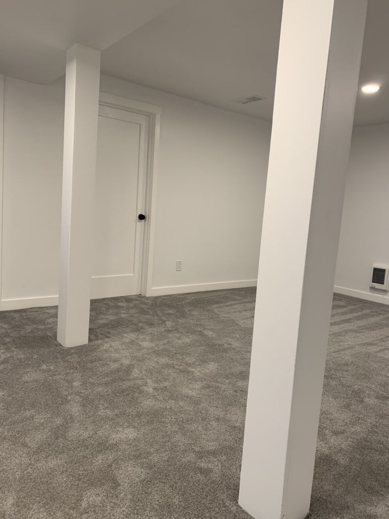 Repainted basement rec room with white walls, columns, and trim by Artbrick