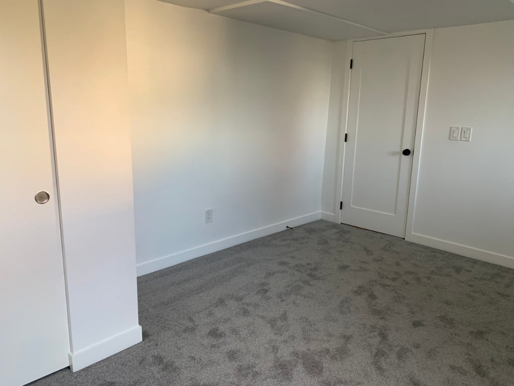 Bedroom with freshly painted white walls, panel door, and trim by Artbrick