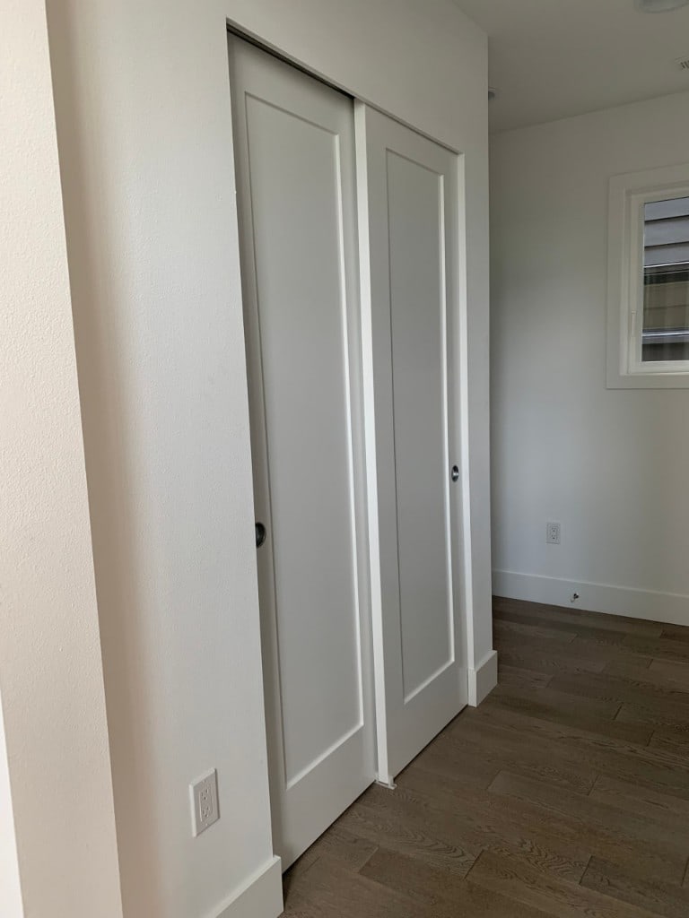 Freshly painted sliding closet doors and trim above hardwood flooring by Artbrick
