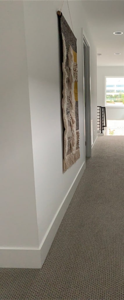 Painted hallway with crisp white walls and trim beside hanging wall art by Artbrick
