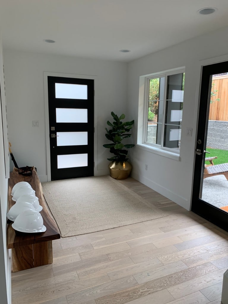 Modern entry foyer with a black glass-panel front door and white oak floors by Artbrick