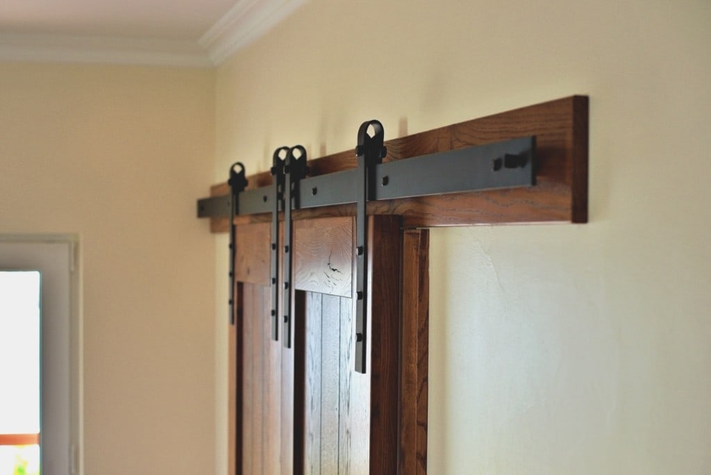 Black sliding barn-door hardware on a stained wood header during an Artbrick interior remodel