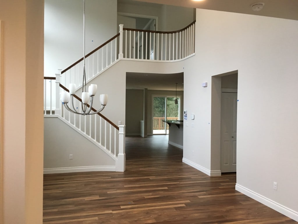 Two-story foyer with a curved staircase and hardwood floors after a whole-home renovation by Artbrick