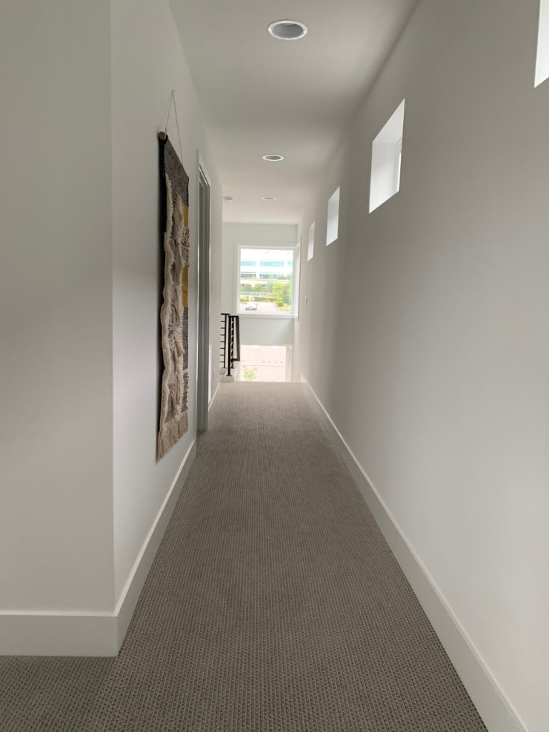 Bright upstairs hallway with square accent windows and new carpet by Artbrick