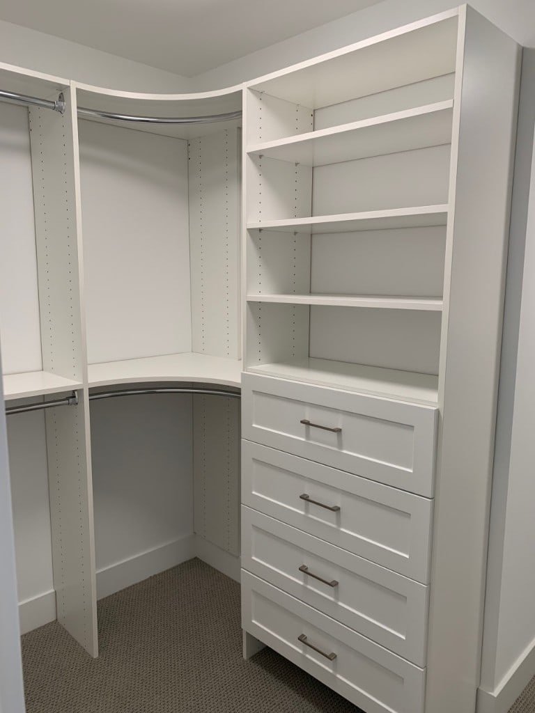 Custom white walk-in closet with corner shelving and drawers by Artbrick