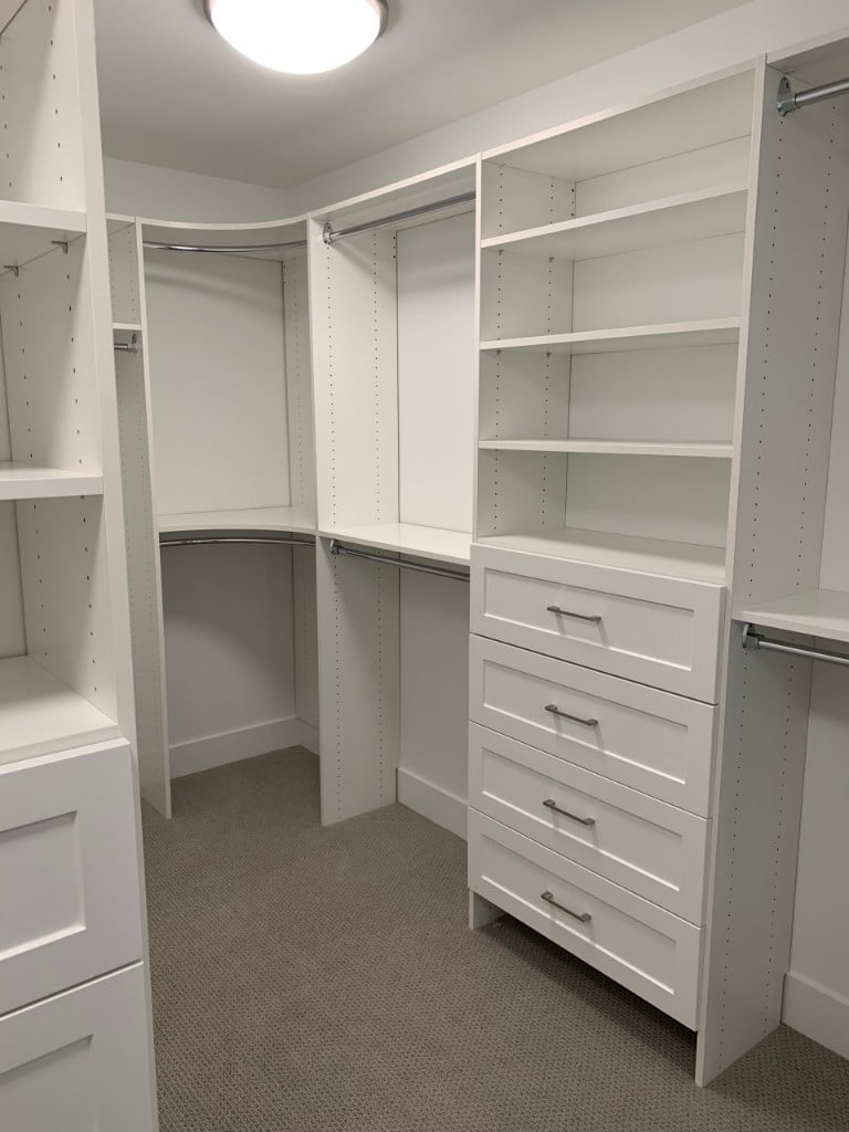 Custom white walk-in closet build with shelving and drawers by Artbrick