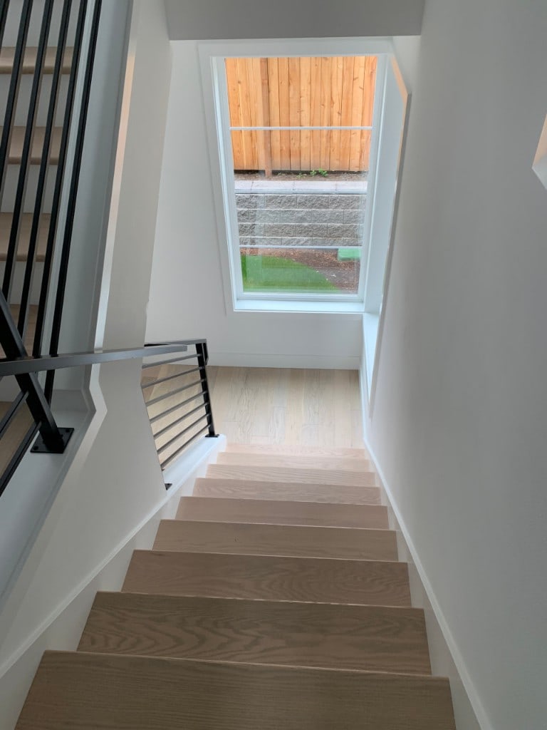 White oak staircase with a modern horizontal metal railing in a whole-home renovation by Artbrick